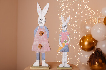 wooden decorative bunnies on a background with balls. Decor for Easter or for a cozy garden.