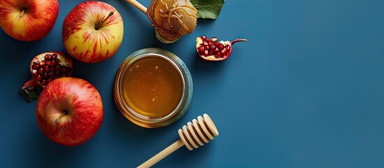 Jewish New Year celebration imagery with honey jar, apples, pomegranate, and shofar on blue backdrop, allowing for text placement with copy space image.