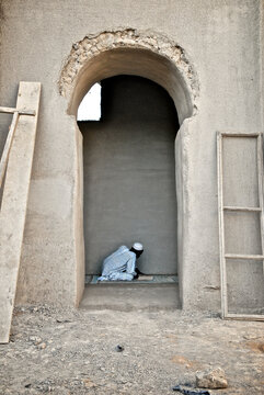 Djenne, Mali - 09 October 2010: View of Muslim man praying at rustic Djenne Mosque, Inland Niger Delta, Mali.