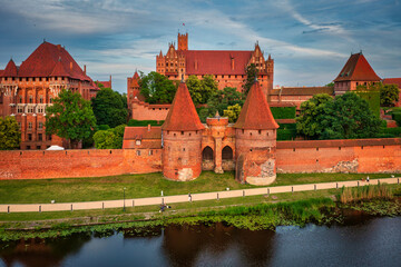 Castle of theTeutonic Order in Malbork by the Nogat river at sunset.