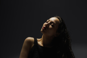 Fototapeta premium Portrait of asian woman with red lips standing under light isolated on grey