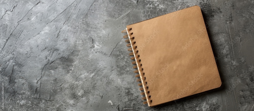 Fototapete top view of a brown kraft paper notebook placed on a gray concrete surface with ample copy space for