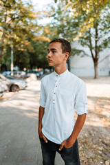 Handsome fashionable teenager standing on city street and posing.