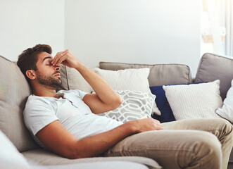 Stress, headache and man on sofa with migraine, fatigue or influenza burnout in his home....