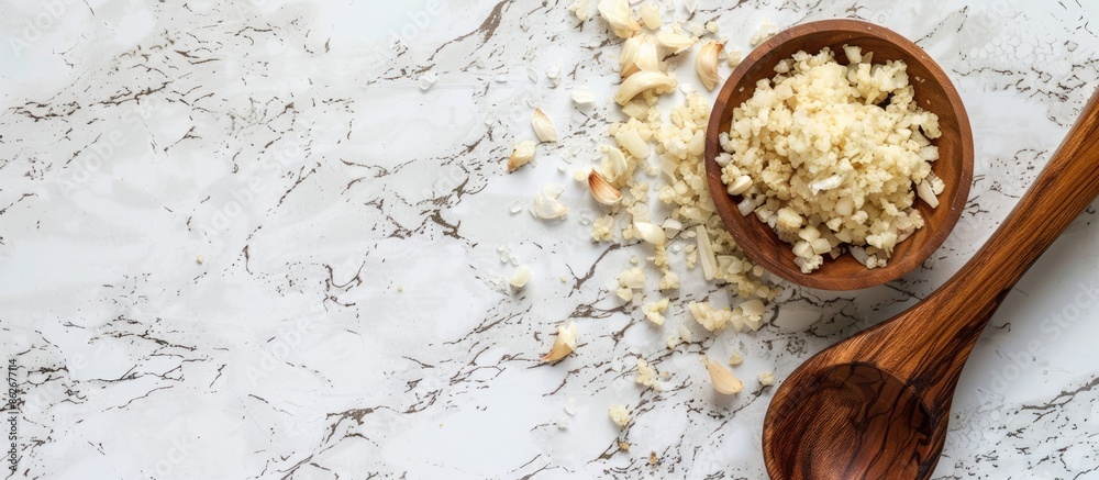 Aufkleber Wooden ladle with minced garlic on a white desk with a plain background, presenting a top view of the copy space image.