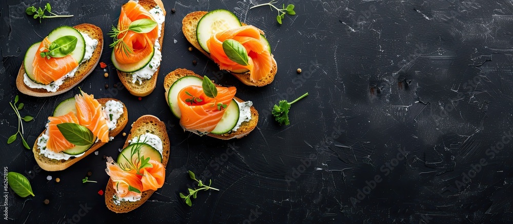 Poster Top view of delicious salmon, cream cheese, and cucumber toasts on a black table with ample copy space image.