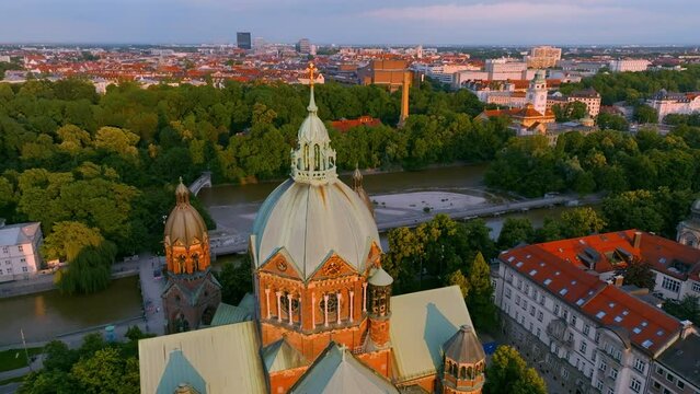 Beautiful evening view of Isar river and Saint Lukas church with city panorama behind in Munich, Germany