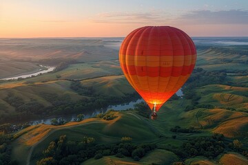 Obraz premium A majestic hot air balloon floating over a picturesque landscape of rolling hills and fields at dawn. 