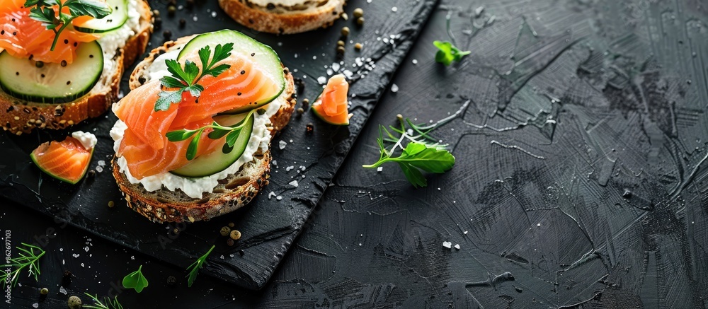 Aufkleber top view of delicious salmon, cream cheese, and cucumber toasts on a black table with ample copy spa