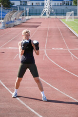 Fototapeta premium young female boxer training in the stadium, standing in position