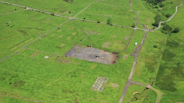 Aerial view of expansive green field, road, trees, and grassland at Stobs Camp, Hawick, Scotland.