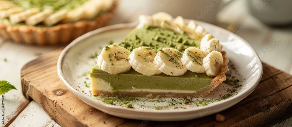 Poster banana-topped matcha banoffee pie on a white plate with a wooden table backdrop for a copy space ima