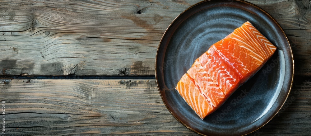 Aufkleber Top view of a cooked salmon fillet on a plate against a wooden background with copy space image.