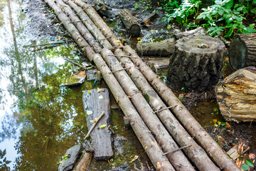 An improvised bridge over a puddle in the forest made from stacked logs