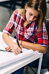 Professional female architect drawing blueprint of construction using stationery and equipment at desktop, creative girl studying design courses in college making drafting sketches for homework