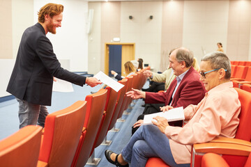 Lecturer distributing form to audience at convention center