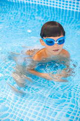 Naklejka premium Boy in glasses chill on water in swimming pool outdoor. Chill, rest and relax. Summertime vacation.