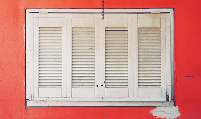 White Wooden Shutters On Red Wall Frontal Close-Up Photo