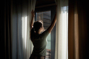 Woman Opening Curtains to Let in Morning Light