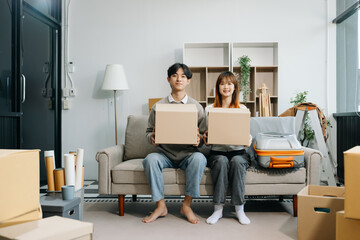 Happy asian young attractive couple man and woman with big boxes moving into a new house, new apartment