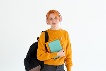 Young college going european redhead hair female nerd student with a backpack, headphones on head,...