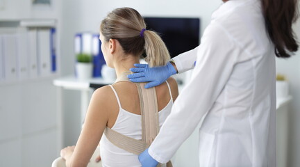 Doctor fixes posture corrector to patient. Slouching, causes, symptoms and treatment