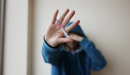 Addict is holding syringe with needle in his hand. Depression and drug addiction concept