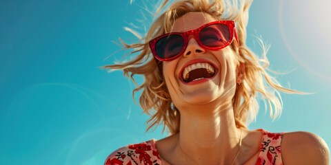 portrait of a blonde woman wearing red sunglasses smiling on the beach, blue sky background