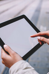 Cropped view of woman's hands holding modern touch pad device with blank screen area for your internet advertise or website content.Female person touching with finger mock up display on tablet