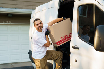 Young delivery man loading cardboard boxes from truck