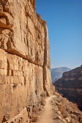 Fototapeta premium A dirt road winding between rocky cliffs in a desert landscape.