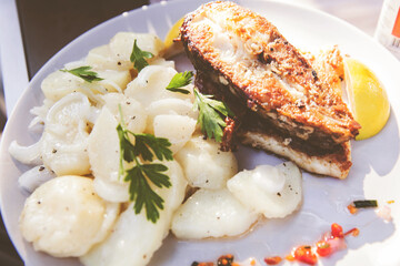 Golden-brown Fried Fish And  Perfectly Seasoned Potatoes Serving On Plate On Restaurant Table