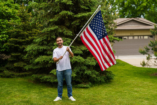 Young handsome man with USA flag in park. 4 July celebration