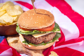 Tasty cheeseburger, chips and sauce with patriotic american flag