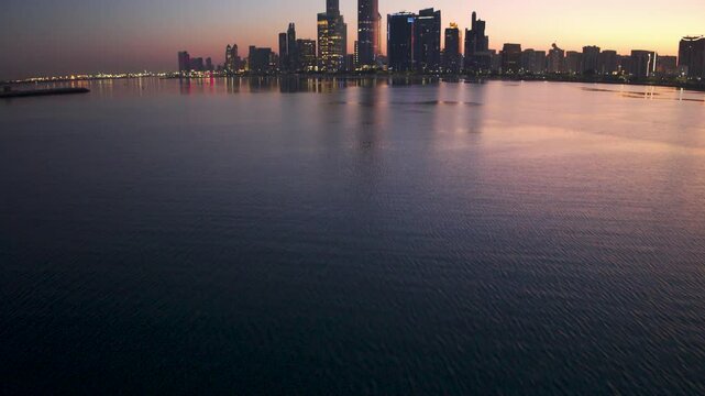 Aerial view of Abu Dhabi skyline with water reflection at sunset, Dubai, United Arab Emirates.