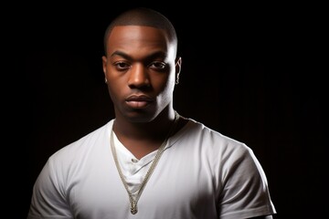 Obraz premium A man with a shaved head and a white shirt with a gold chain around his neck