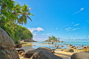 Anse royale beach, Mahe, blue sky turquoise water, low tide sunny day, white sandy beach and granite rock boulders, Seychelles 