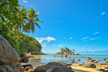 Anse royale beach, Mahe, blue sky turquoise water, low tide sunny day, white sandy beach and granite rock boulders, Seychelles 