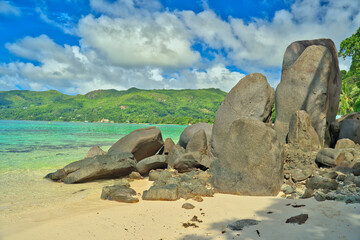 Anse royale beach, Mahe, blue sky turquoise water, low tide sunny day, white sandy beach and granite rock boulders, Seychelles 