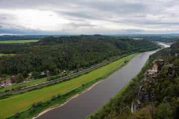 A river with a train passing by. The train is long and it is moving
