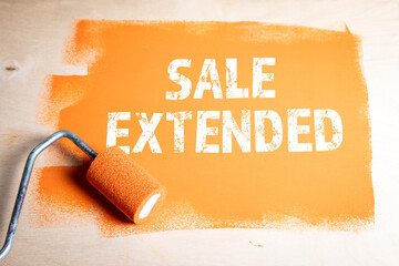 Sale Extended. Orange paint and paint roller on wooden background