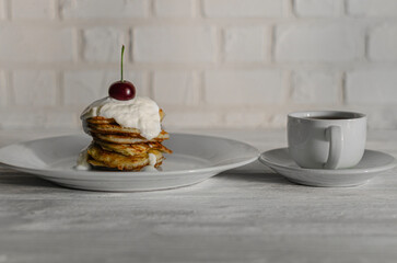 Stack of pancakes with cherries and cream