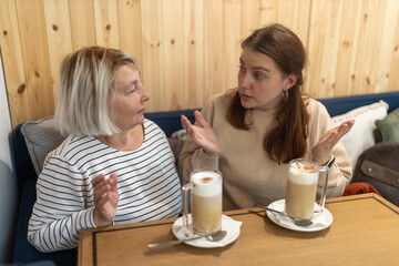 Group women enjoying fun conversation with cup of coffee at indoor restaurant. Lifestyle concept, two people. Two female sit in the cafeteria, chatting and gossiping