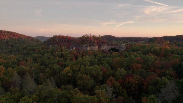 Sunset Colorful Forest Aerial Epic Natural Bridge Stone Formation. Tourist Destination Red River Gorge Kentucky in Autumn Fall Foliage. Fly Towards Bridge.