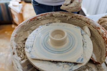 Using potter wheel, professional potter creates bowl from wet soft clay