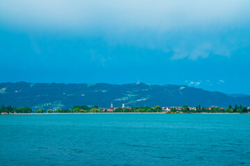 Germany, Lindau island city houses at bodensee lake water panorama view to austrian mountains, alps, pfaender peak and nature landscape after sunset