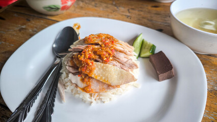 Hainanese chicken both steamed and fried chicken served with Hainanese oily rice, dipping sauces, and chicken clear soup. Thai famous Street food.