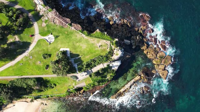 Aerial view of coastal park with rocky shore and pathway at Giles Baths, Coogee, Bali Memorial, Goldstein Reserve, Sydney, New South Wales, Australia.
