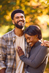 Loving Young Couple Hugging Against Background Of Autumn Leaves In Garden Or Countryside