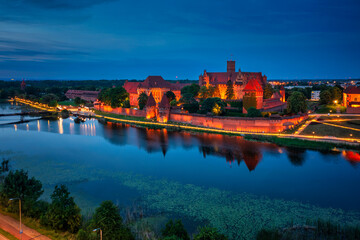Castle of theTeutonic Order in Malbork by the Nogat river at dusk.